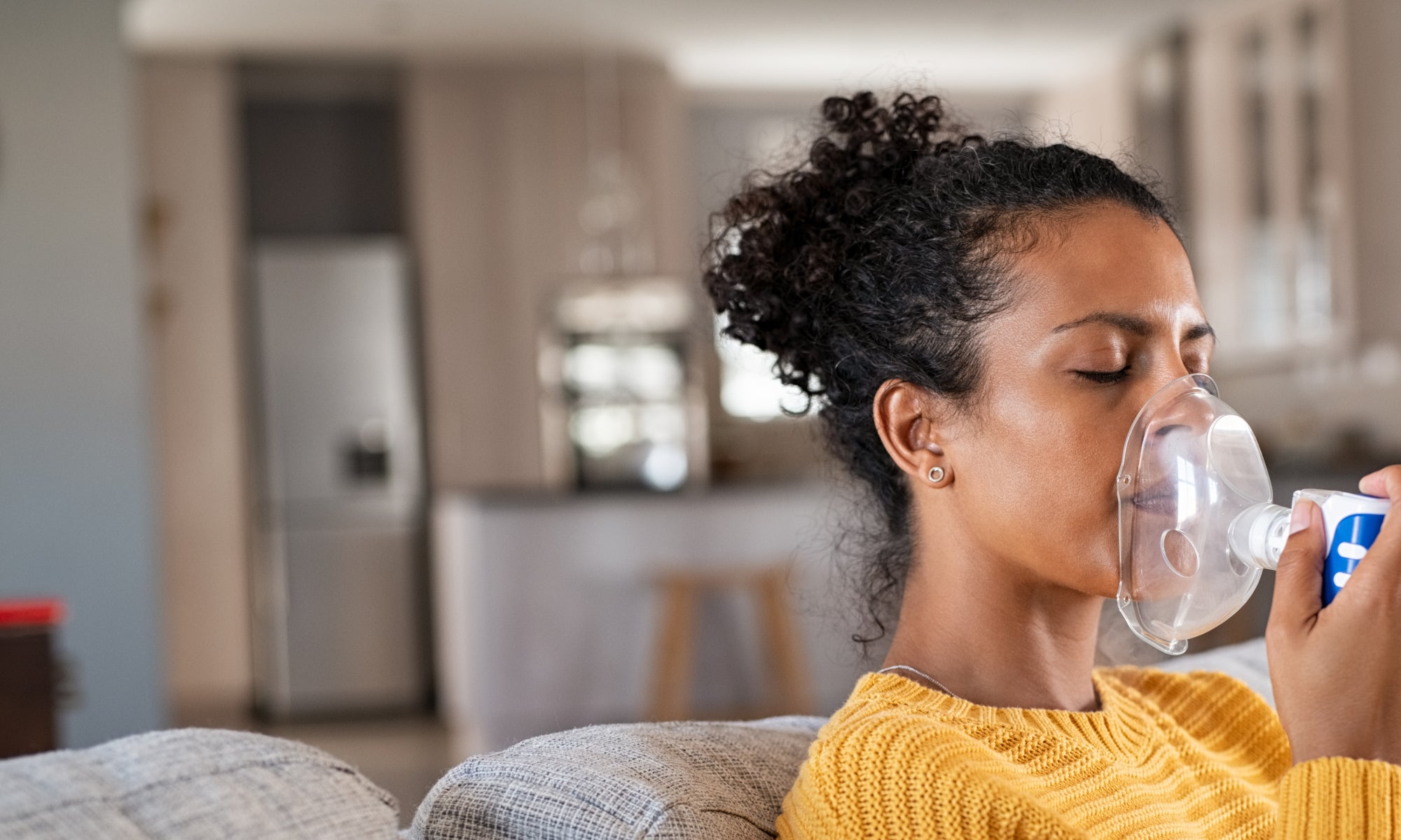 african american woman using nebulizer inhaler at home